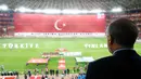 Bendera Turki di layar raksasa berkibar saat lagu kebangsaan negara asal Arda Turan itu berkumandang.  Presiden Turki, Tayyip Erdogan bersama para pemain dan penonton tampak khidmat. (AFP/Kayhan Ozer)