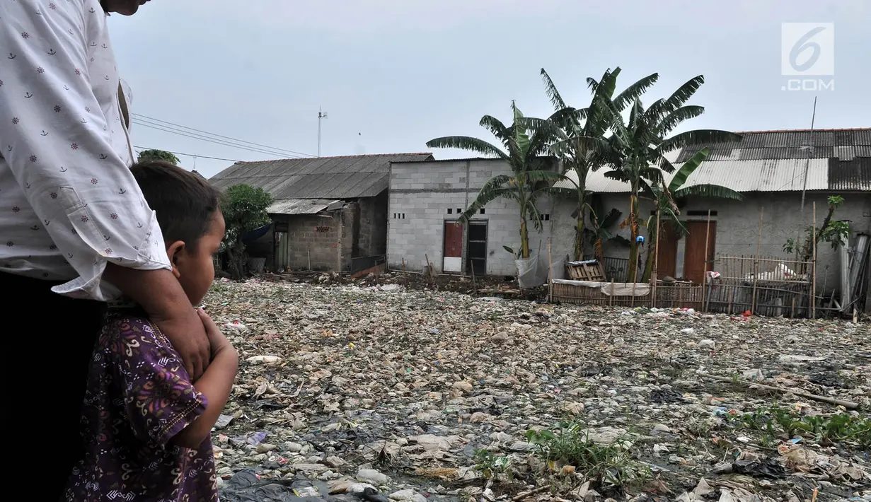 Warga bersama anaknya melihat sampah yang memenuhi Kali Pisang Batu, Bekasi, Jawa Barat, Rabu (9/1). Warga tetap beraktivitas sehari-hari meski bau tak sedap menghantui mereka akibat tumpukan sampah di Kali Pisang Batu. (Merdeka.com/Iqbal S. Nugroho)