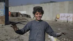 Seorang anak tersenyum di tempat pembuangan sampah di Kabul, Afghanistan (15/12/2019). Menurut statistik PBB, Afghanistan adalah salah satu negara termiskin di dunia di mana anak-anak menjadi sasaran kemiskinan dan kekerasan ekstrem setiap hari.  (AP Photo/Altaf Qadri)