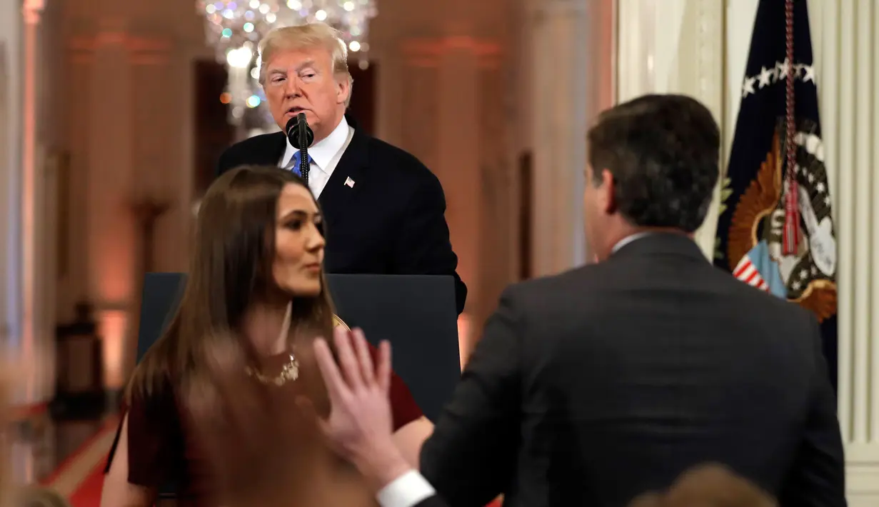 Presiden AS, Donald Trump menatap ke arah ke jurnalis CNN, Jim Acosta saat seorang staf mencoba menarik mikrofon darinya dalam konferensi pers di Gedung Putih, Rabu (7/11). Ketegangan bermula dari pertanyaan sang wartawan soal imigran. (AP/Evan Vucci)