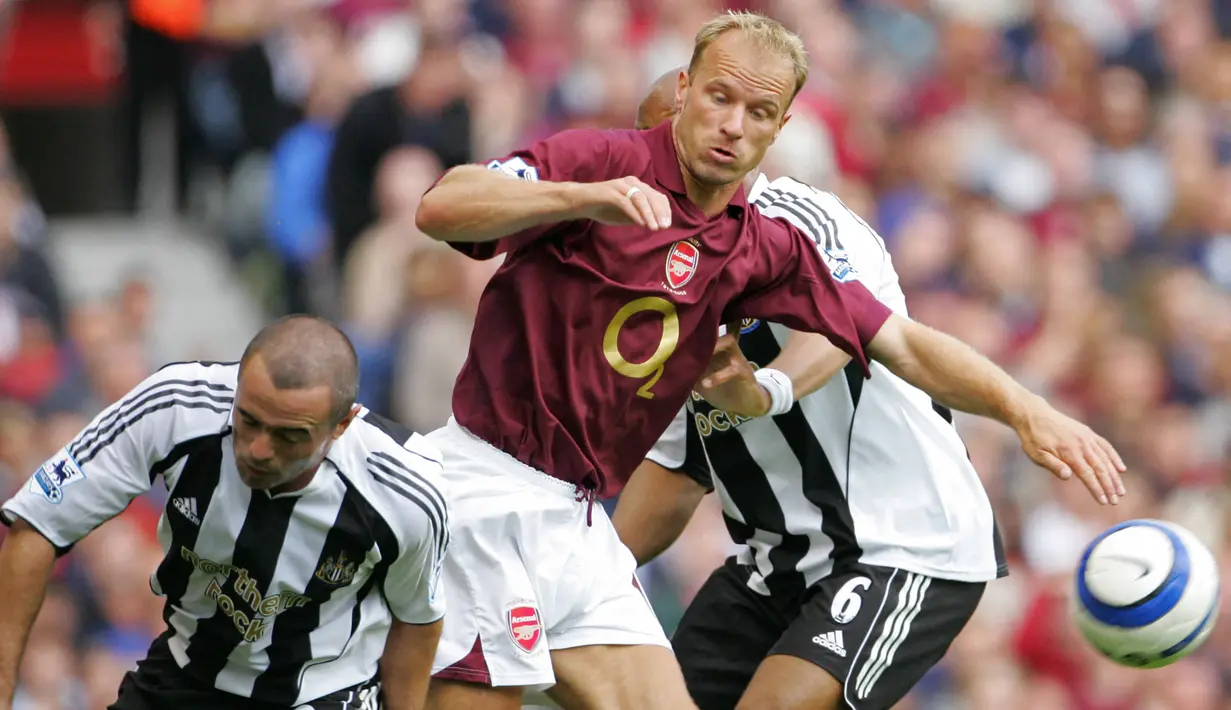 Striker Arsenal, Dennis Bergkamp (tengah) berebut bola dengan bek Newcastle United, Stephen Carr pada laga Liga Inggris 2005/2006 di Highbury Stadium, London (14/8/2005). Dennis Bergkamp didatangkan Arsenal dari Inter Milan pada awal musim 1995/1996. The Gunners harus mengeluarkan mahar sebesar 11,25 juta euro. Bertahan selama 11 musim di Arsenal hingga pensiun pada Juli 2006, ia total bermain dalam 417 laga dengan torehan 119 gol dan 98 assist. (AFP/Odd Andersen)