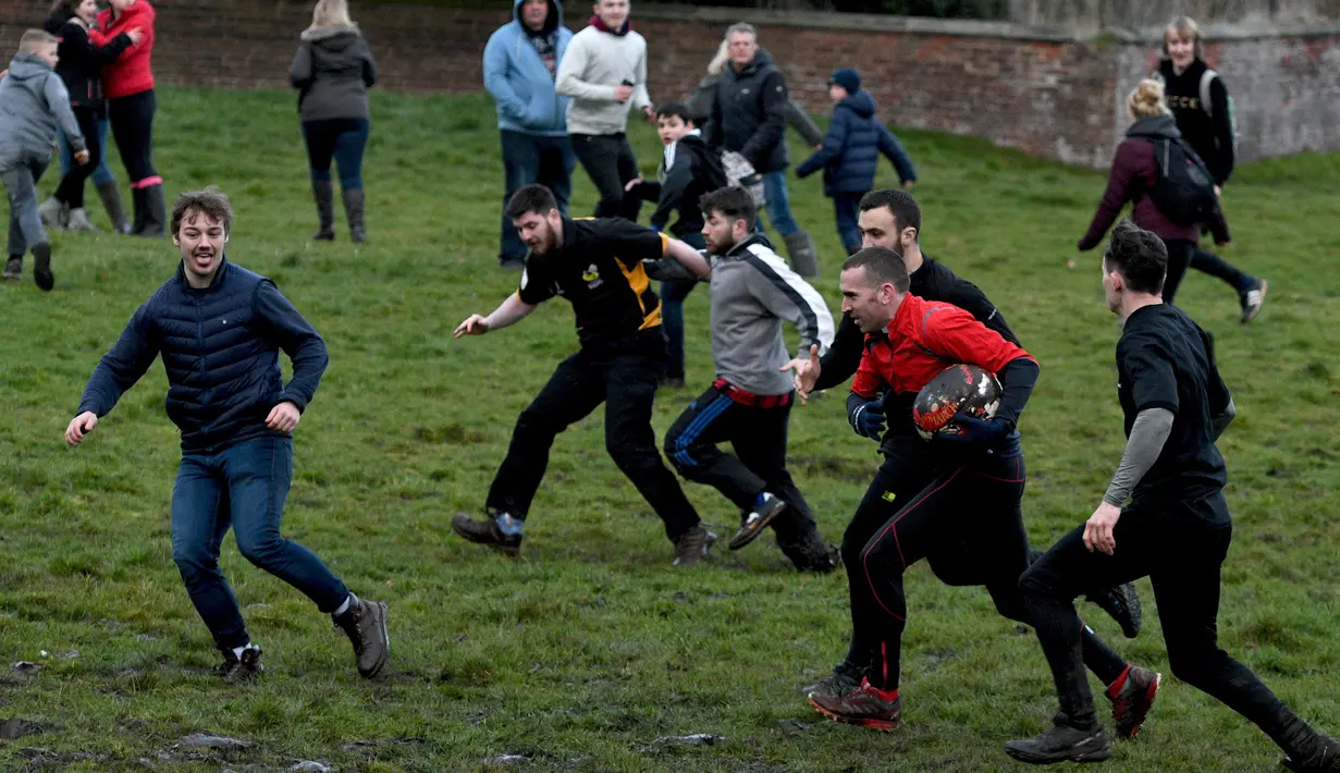Seorang pria membawa bola saat mengikuti Royal Shrovetide Football Match di Ashbourne, Derbyshire, Inggris, Selasa (5/3). Pertandingan ini bertujuan untuk meletakkan sebuah bola ke gawang yang berjarak 3 mil (4,8 kilometer). (Oli Scarff/AFP)