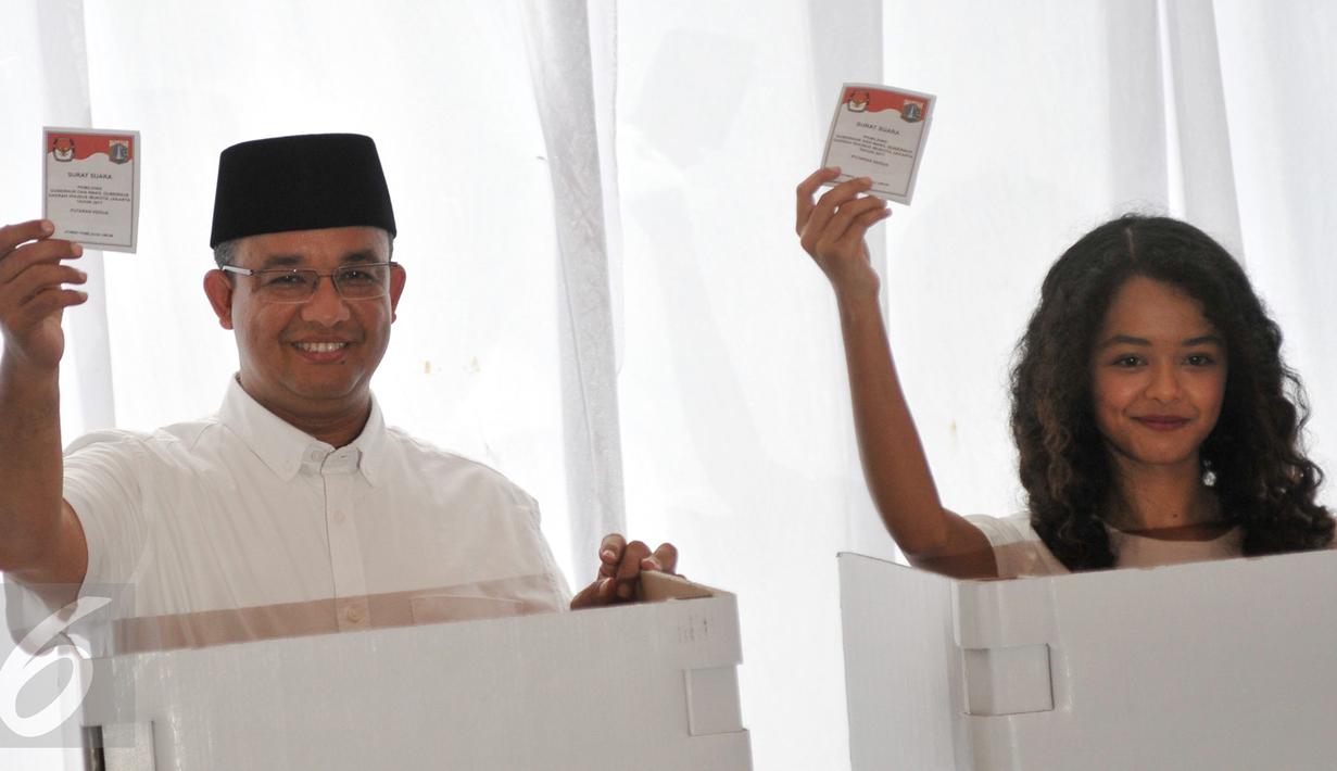 Anies Baswedan bersama anaknya menunjukan kertas suara sebelum memasukan ke kotak saat menggunakan hak pilihnya di TPS 28 Cilandak, Jakarta Selatan, Rabu (19/4). (Liputan6.com/Yoppy Renato)