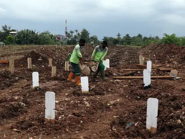 Petugas membersihkan area khusus pemakaman jenazah dengan protokol COVID-19 di TPU Srengseng Sawah Dua, Jakarta, Selasa, (2/2/2021). TPU Srengseng Sawah 2, saat ini mulai menerima pemakaman jenazah protokol COVID-19 dengan kapasitas 1.020 petak. (Liputan6.com/Helmi Fithriansyah)