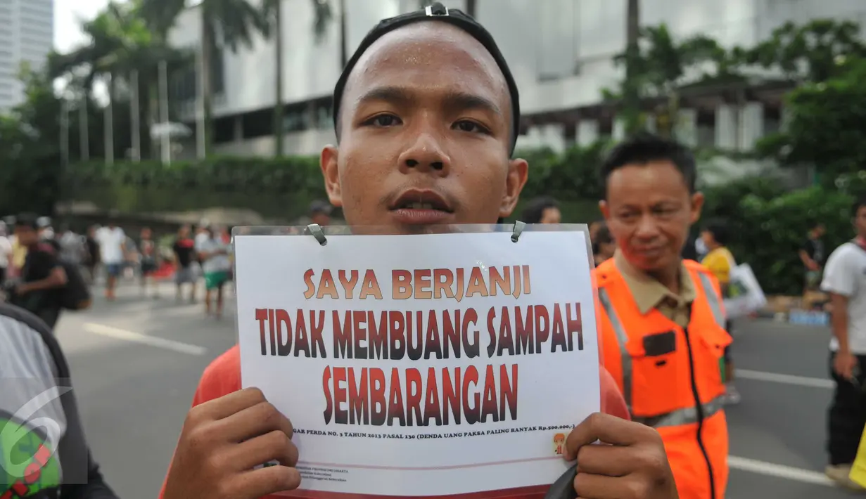 Seorang warga menunjukkan tulisan "Saya Berjanji Tidak Membuang Sampah Sembarangan" saat menjalani sidang karena tertangkap membuang sampah sembarangan di kawasan Bundaran HI, Jakarta, Minggu (24/4).(Liputan6.com/ Gempur M Surya)