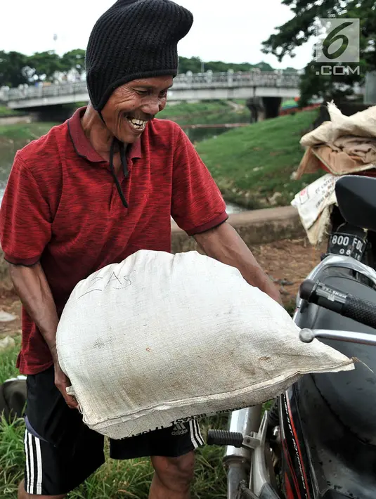 Pak Sum mengangkut cacing super hasil tangkapannya ke sepeda motor di Kanal Banjir Timur, Jakarta, Kamis (14/2). Cacing super hasil tangkapan nantinya akan dijual untuk memenuhi kebutuhan pedagang ikan hias. (Merdeka.com/Iqbal Nugroho)
