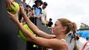 Petenis Italia, Camila Giorgi menandatangi bola yang disodorkan penggemarnya setelah menang atas Iga Swiatek dari Polandia pada pertandingan putaran kedua turnamen Australia Terbuka di Melbourne, Kamis (17/1). (AP Photo/Andy Brownbill)