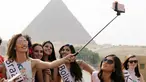 Kontestan Miss ECO Universe berselfie menggunakan tongsis dengan latar belakang segitiga piramida di pinggiran Kairo, Mesir (10/4). Pemenang Miss Eco Universe 2016 akan memenangkan hadiah uang tunai USD 10.000. (REUTERS/Mohamed Abd El Ghany)