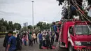 Petugas pemadam kebakaran membawa seorang anak saat akan mencoba wahana flying fox di area Monas, Jakarta, Selasa (1/1). Wahana ini dihadirkan agar pengunjung bisa merasakan serunya menjadi pemadam kebakaran. (Liputan6.com/Faizal Fanani)