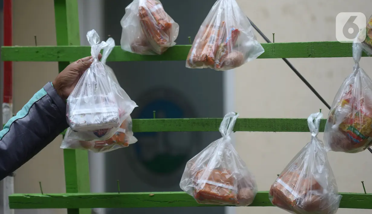 Pengemudi ojek online mengambil sembako yang digantung di rak kayu di kawasan Rawa Barat, Jakarta Selatan, Kamis (14/5/2020). Selama masa pandemi COVID-19, pihak kelurahan dan masjid sekitar menyediakan paket berisi mi instan, telur, dan masker untuk warga yang membutuhan. (merdeka.com/Imam Buhori)