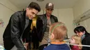 Pemain Barcelona, Marc Bartra (kiri) dan Neymar berbincang dengan salah satu pasien anak saat melakukan kunjungan amal di Rumah Sakit Vall d' Hebron, Barcelona, Senin (4/1/2016). (AFP PHOTO / Josep LAGO)