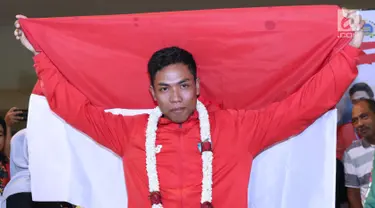 Pelari muda Indonesia, Lalu Muhammad Zohri membentangkan bendera Merah Putih saat penyambutan di Terminal 3 Bandara Soetta, Tangerang, Selasa (17/7). Lalu M Zohri meraih emas lari 100m putra di Kejuaraan Dunia U-20 IAAF. (Liputan6.com/Helmi Fithriansyah)