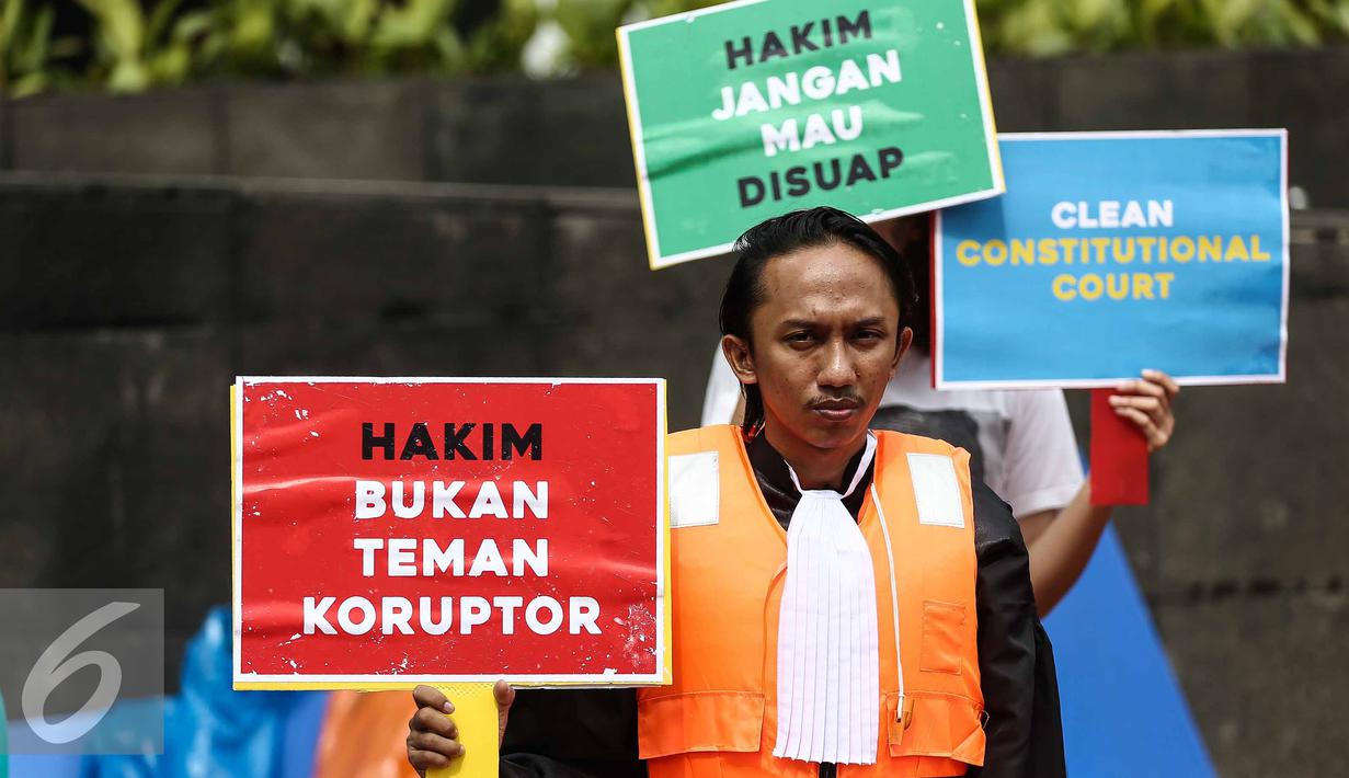 Seorang anggota Indonesia Corruption Watch (ICW) menunjukan poster saat menggelar aksinya di Car Free Day dikawasan Bunderan HI, Jakarta, Minggu (12/2). (Liputan6.com/Faizal Fanani)