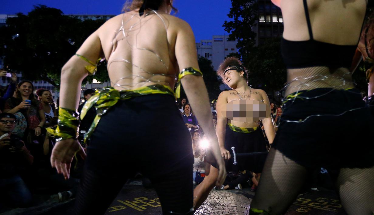 Seorang wanita dari sebuah kelompok seni bertelanjang dada saat berunjuk rasa memprotes maraknya pemerkosaan dan kekerasan seksual di pusat kota Rio de Janeiro, Brasil, Rabu (1/6). (REUTERS/Ricardo Moraes)