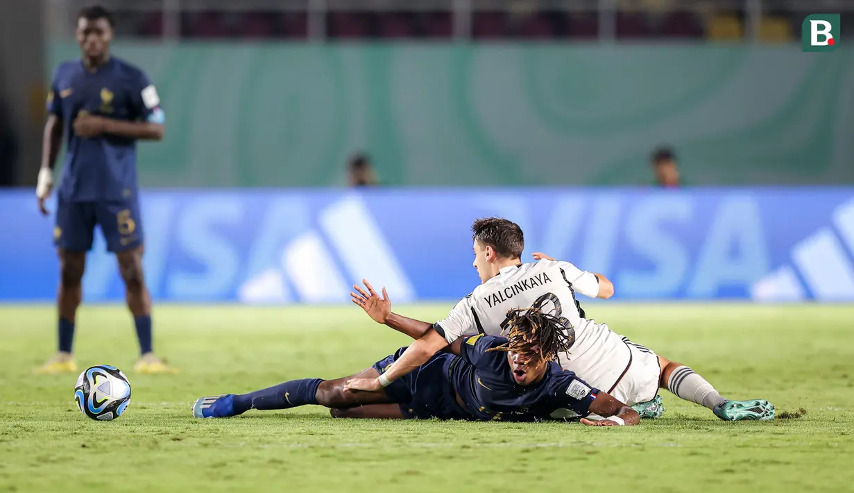 <p>Pemain Timnas Prancis U-17, Fode Sylla (kiri) dan pemain Timnas Jerman U-17, Bilal Yalcinkaya terjatuh saat perebutan bola pada laga final Piala Dunia U-17 2023 di Stadion Manahan, Solo, Sabtu (2/12/2023). (Bola.com/Bagaskara Lazuardi)</p>