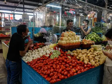 Pelanggan membeli sayuran di sebuah kios dengan sekat tirai pelindung plastik di pasar La Asuncion di Villa Nueva, Guatemala City pada 20 Juli 2020. Kios di pasar itu menggunakan tirai pelindung plastik untuk menjaga jarak fisik guna mengurangi resiko penyebaran virus Corona. (Johan ORDONEZ/AFP)