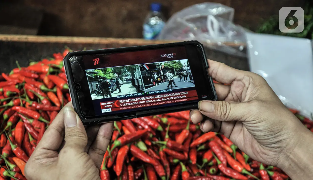 Pedagang menyaksikan tayangan pada gawainya yang menyiarkan langsung rekonstruksi pembunuhan Brigadir Nofriansyah Yosua Hutabarat alias Brigadir J melalui smartphone di Pasar Senen, Jakarta Pusat, Selasa (30/8/2022). Rekonstruksi ulang pembunuhan Brigadir J yang dihadiri oleh lima tersangka, yakni Ferdy Sambo, Bharada Richard Eliezer (Bharada E), Bripka Ricky Rizal, Kuat Ma'ruf, dan Putri Candrawathi itu menjadi perhatian warga dari berbagai kalangan untuk menyaksikan secara langsung meski hanya melalui siaran televisi atau gawai. (merdeka.com/Iqbal S. Nugroho)