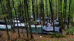 Migran berdiri di sekitar tenda yang dibuat seadanya di kamp darurat di hutan di luar Velika Kladusa, Bosnia pada 26 September 2020. Kebanyakan imigran dan pengungsi di Bosnia berasal dari Timur Tengah, Afrika dan Asia. (AP Photo/Kemal Softic)