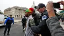 Petugas polisi mengamankan demonstran bernama Jerome Waite saat menggelar aksinya di dekat gedung Capitol di Washington (24/4). (AP Photo/Alex Brandon)