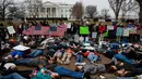 Belasan siswa SMA bersama dengan pengunjuk rasa berbaring di jalan depan Gedung Putih, Washington, Senin (19/2). Mereka memprotes mengenai peraturan pengendalian senjata di Amerika Serikat. (AP Photo/Evan Vucci)
