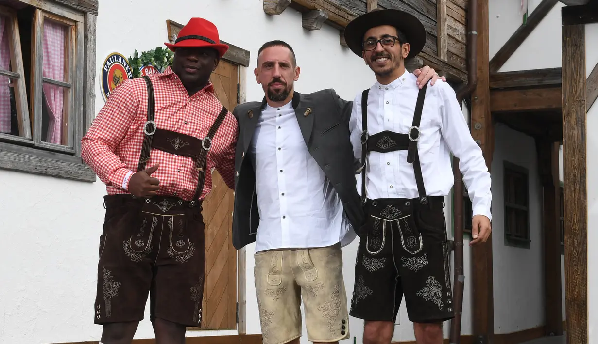 Pemain Bayern Munchen Franck Ribery (tengah) mengenakan gaun tradisional Bavaria, Lederhosen, saat berpose dengan dua orang teman setibanya pada festival bir tahunan Oktoberfest di Munich, Jerman, Minggu (7/10). (Christof STACHE / AFP)