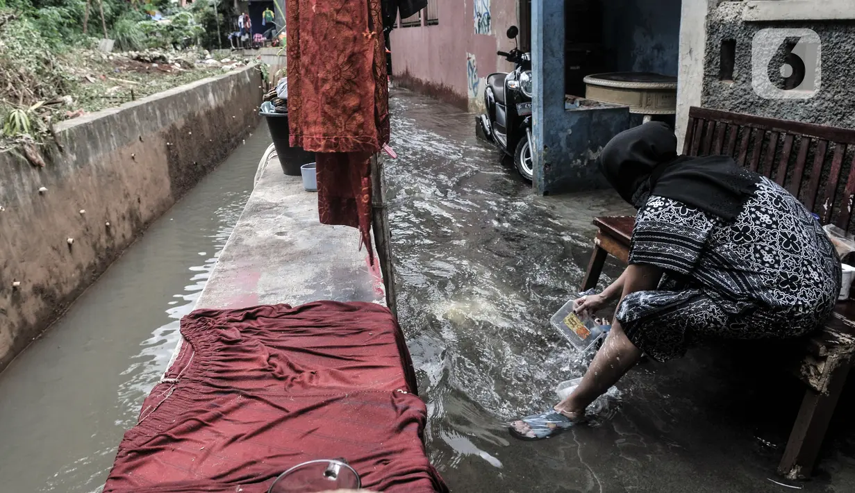 Warga mencuci pakaian saat banjir merendam permukiman warga di kawasan Kemang Timur XI, Jakarta Selatan, Minggu (21/2/2021). Ketinggian air mencapai sepinggang orang dewasa. (merdeka.com/Iqbal S. Nugroho)