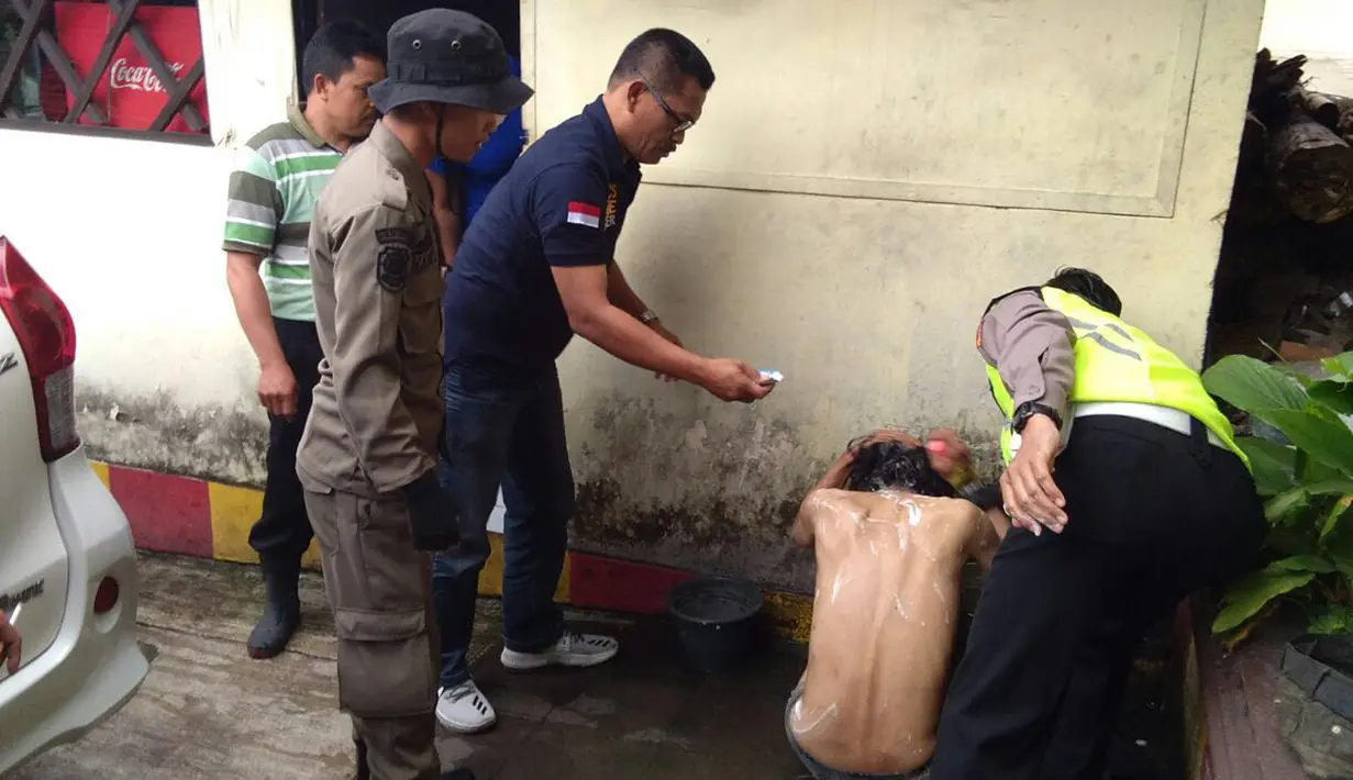 Petugas memandikan salah satu orang dengan gangguan jiwa yang berhasil diamankan di Kabupaten Bogor, Jawa Barat, Rabu (14/2). Setelah itu, mereka dibawa ke Dinas Sosial (Dinsos) Kabupaten Bogor untuk penanganan lebih lanjut. (Liputan6.com/HO/Polres Bogor)