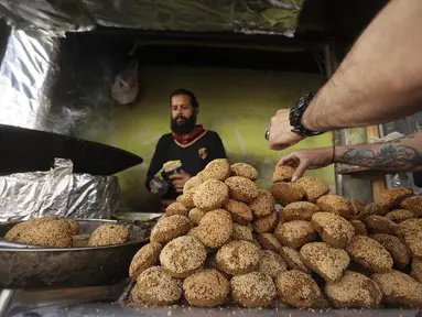 Seorang warga Palestina membuat falafel, makanan yang disukai untuk berbuka puasa, selama bulan suci Ramadhan di pusat kota kota Hebron di Tepi Barat yang diduduki (9/4/2022). Falafel adalah sebuah makanan Timur Tengah. (AFP/Hazem Bader)
