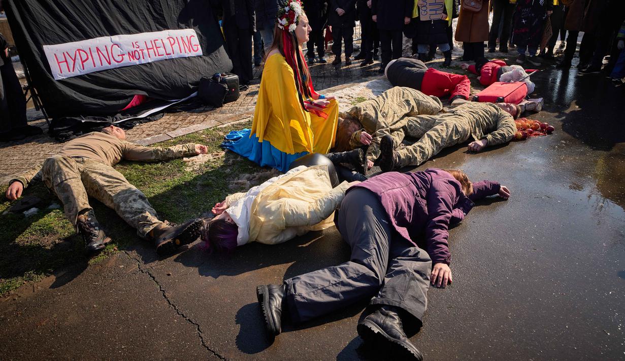 Krisis kemanusiaan tak terelakkan. Tampak dalam foto, orang-orang berpartisipasi dalam pertunjukan seni yang menggambarkan serangan Rusia saat anggota komunitas Ukraina menggelar protes untuk menandai tahun keempat sejak dimulainya invasi skala penuh Rusia ke Ukraina di Bukares, Rumania, Minggu 22 Februari 2026. (AP Photo/Vadim Ghirda)