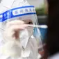 Petugas medis mengambil sampel swab dari seorang warga untuk tes virus corona Covid-19 di Wuhan, Provinsi Hubei, China tengah,  Selasa (22/2/2022). Wuhan, wabah besar pertama dari pandemi virus corona melaporkan lebih dari selusin kasus virus corona baru minggu ini. (AFP/China Out)
