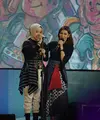 Potret keren Putri Ariani tampil di atas panggung bersama Najwa Shihab. Putri mengenakan atasan dari padu padan tenun dan lurik bernuansa hitam, dipadu celana panjang beige yang serasi dengan hijab polosnya. [Foto: Instagram/arianinismaputri]