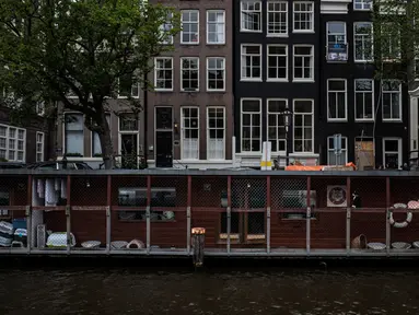 Pejalan kaki melintas dekat Catboat, tempat penampungan berbentuk kapal yang terapung di Amsterdam, Belanda, 3 Agustus 2017. Catboat sangat terkenal sebagai tempat perlindungan untuk para kucing jalanan yang terlantar. (AP Photo/Muhammed Muheisen)