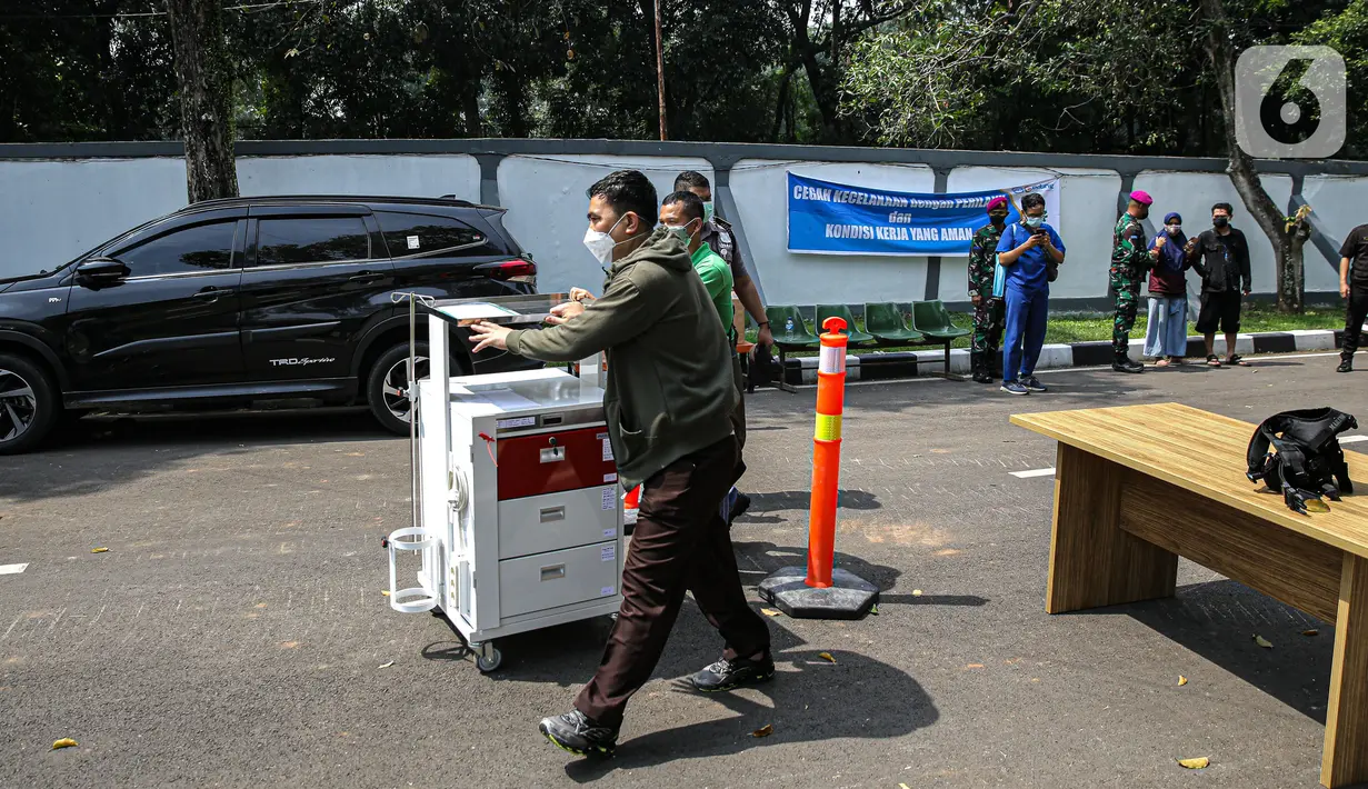 Petugas membawa peralatan medis saat hari pertama pengoperasian Rs Darurat Covid Asrama Haji Pondok Gede, Jakarta, Sabtu (10/7/2021). Presiden Joko Widodo secara resmi mengumkan asara haji pondok gede difungsikan sebagai rumah sakit darurat Covid-19 pada Jumat (9/7). (Liputan6.com/Faizal Fanani)