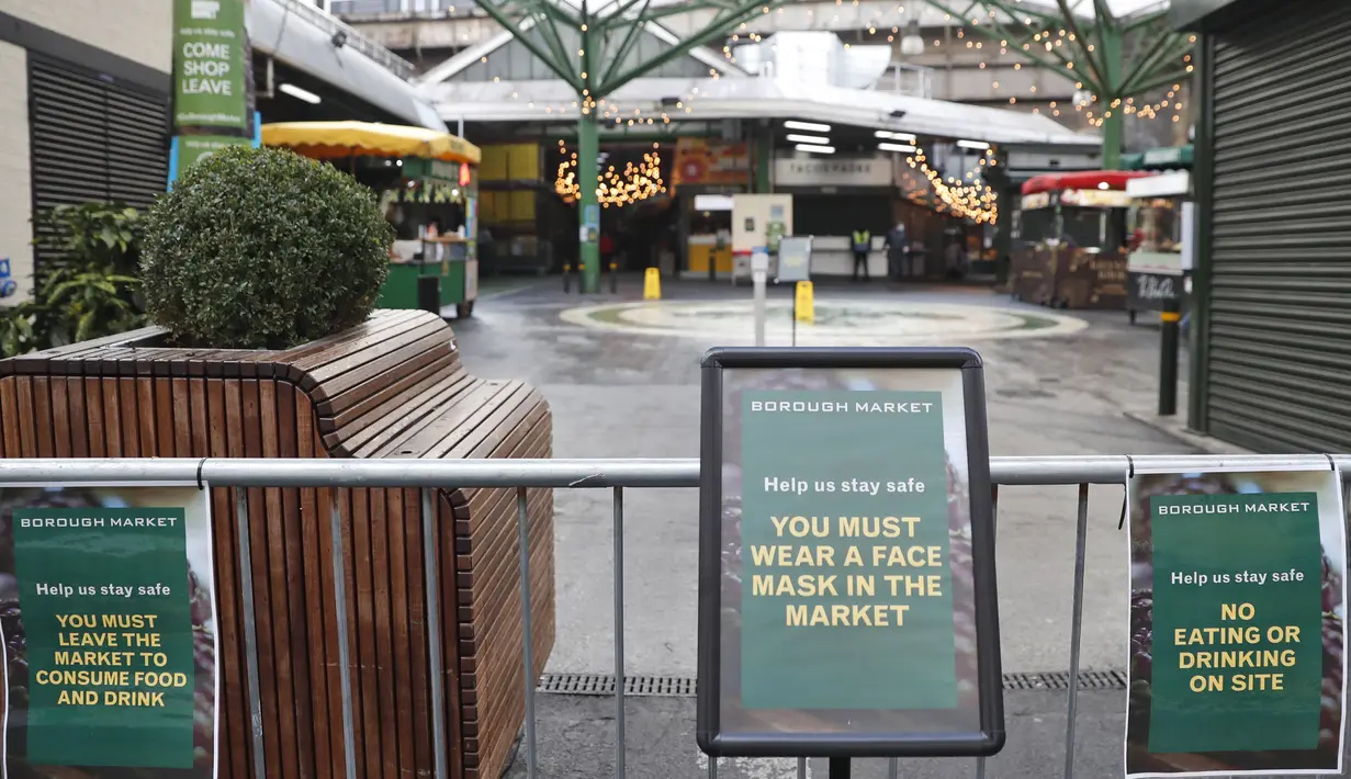 Tanda yang memberitahu pengunjung untuk memakai masker dipasang di pintu masuk Borough Market di London selatan selama penguncian nasional (lockdown) ketiga Inggris, Selasa (12/1/2021). Borough Market menjadi tempat pertama yang mewajibkan pemakaian masker di luar ruangan. (AP Photo/Alastair Grant)