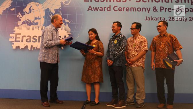 Charge d'affaires a.i., Delegation of the European Union to Indonesia and Brunei Darussalam Charles-Michel Geurts memberikan hadiah kepada penerima beasiswa Uni Eropa  saat Award Ceremony, Pre-Deperture Orientation and Alumni Gathering di Jakarta, Minggu (28/7/2019). (Liputan6.com/Angga Yuniar)