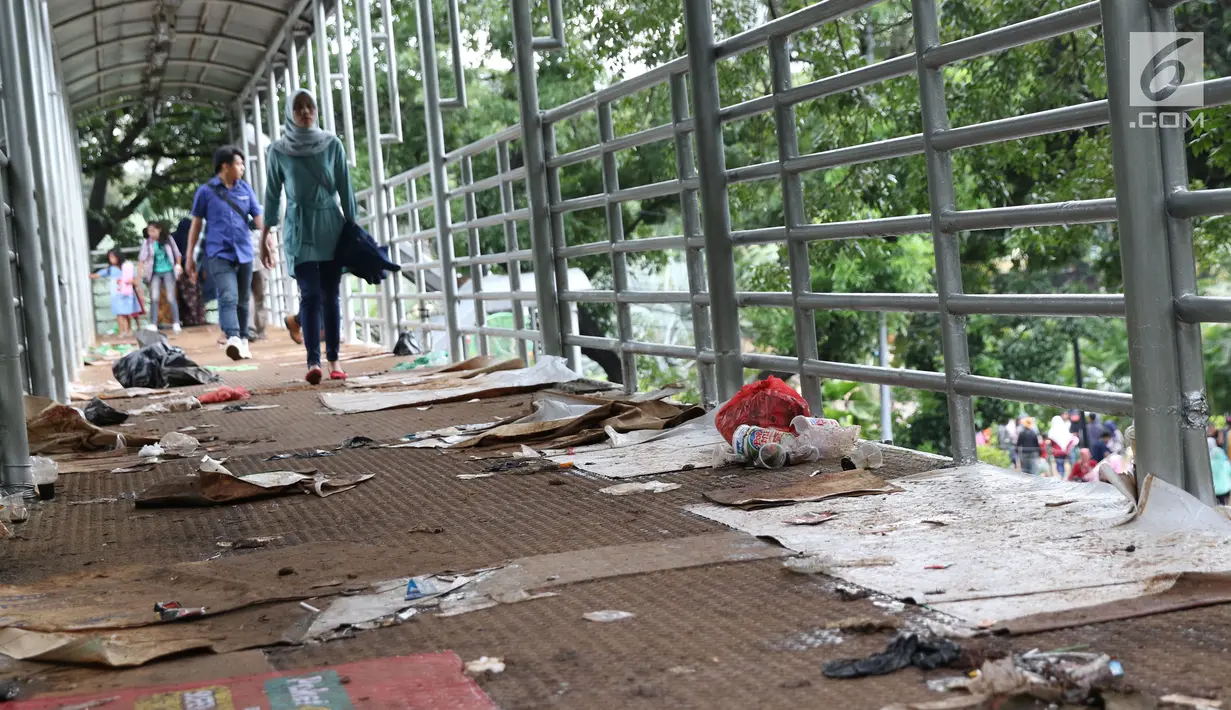 Sampah berserakan di koridor Jembatan Penyebrangan Orang (JPO) Jalan Medan Merdeka Barat, Jakarta, Selasa (1/1). Pasca malam perayaan pergantian tahun JPO Medan Merdeka Barat masih tampak kotor. (Liputan6.com/Helmi Fithriansyah)