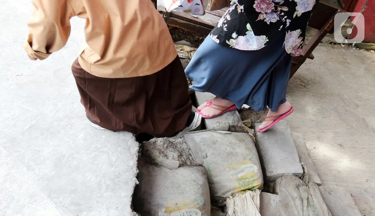 Seorang siswa berjalan keluar melintasi jalan darurat yang dibuat pihak sekolah di SDN Pondok Cina 1, Depok, Jawa Barat, Rabu (9/11/2022). Pembangunan trotoar Jalan Margonda Raya yang tidak membuat jalan darurat untuk siswa tersebut menghalangi pintu masuk SDN Pondok Cina 1 serta membahayakan siswa. (Liputan6.com/Herman Zakharia)