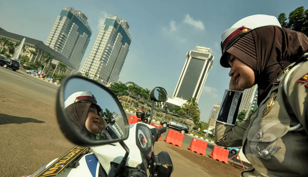 Seorang polwan berjilbab terlihat sedang bersiap sebelum memulai tugas di pelataran Silang Monas, Jakarta, Jumat (27/3/2015). Polwan di seluruh Indonesia akhirnya diperbolehkan mengenakan jilbab. (Liputan6.com/Faizal Fanani)