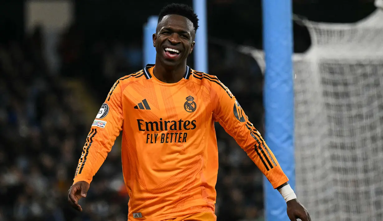 Pemain Real Madrid, Vinicius Junior tertawa saat laga leg 1 babak playoff Liga Champions 2024/2025 melawan Manchester City di Etihad Stadium, Manchester, Inggris, Rabu (12/02/2025) WIB. (AFP/Oli Scarff)