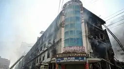 Petugas pemadam kebakaran dan tim SAR masih menyisir area gedung untuk memastikan tidak ada korban yang terjebak di bawah puing-puing. Tampak dalam foto, petugas pemadam kebakaran dan tim penyelamat melakukan operasi pendinginan di tengah puing-puing setelah kebakaran besar di sebuah pusat perbelanjaan di Karachi pada Senin 19 Januari 2026. (Asif HASSAN/AFP)