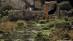Seorang pemuda Libya menaiki tangga di situs kota Yunani kuno Kirene yang didirikan pada tahun 630 SM sebagai koloni Thira (Santorini), di pinggiran kota Shehhat di sebelah timur pantai kota Benghazi di pantai Libya (13/12/2019). Situs Kirene terletak di sebuah lembah yang subur di dataran tinggi Je