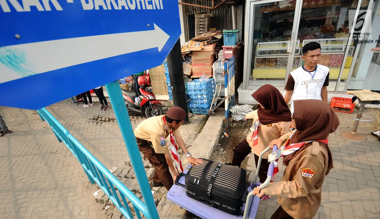 Anggota Pramuka mengangkat troli dan barang bawaan pemudik di kawasan Pelabuhan Merak, Banten, Kamis (22/6). Di Pelabuhan Merak, sejumlah anggota Pramuka diterjunkan untuk membantu pemudik membawa barang bawaan. (Liputan6.com/Helmi Fithriansyah)