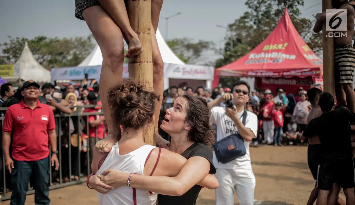 Warga negara asing mengikuti panjat pinang kolosal dalam rangka merayakan HUT ke-74 Kemerdekaan RI di Pantai Karnaval, Ancol, Jakarta, Senin (17/8/2019). Sebanyak 174 batang pinang dengan beragam hadiah disediakan dalam lomba yang diikuti ratusan warga itu. (Liputan6.com/Faizal Fanani)