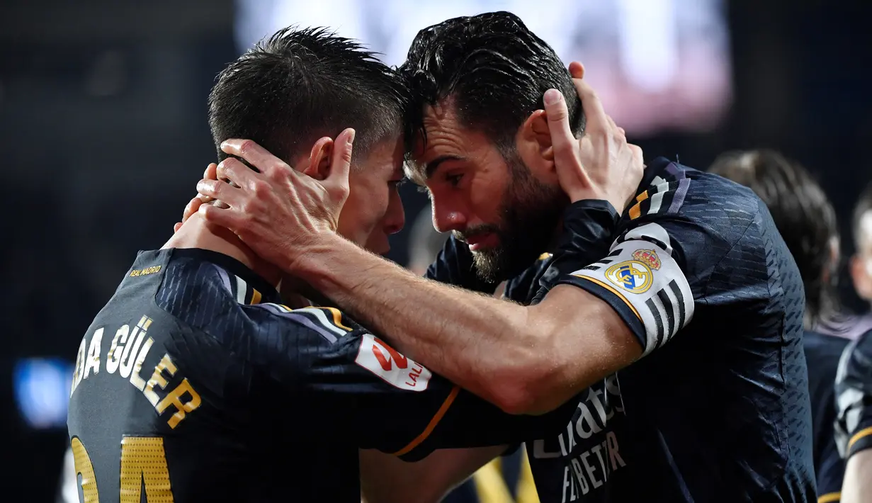 Gelandang Real Madrid #24 Arda Guler (kiri) merayakan dengan bek Real Madrid #06 Nacho Fernandez setelah mencetak gol pertama timnya ke gawang Real Sociedad pada pertandingan pekan ke-33 La Liga 2023/2024 di Stadion Anoeta, Sabtu (27/04/2024) dini hari WIB. (Ander Gillenea / AFP)