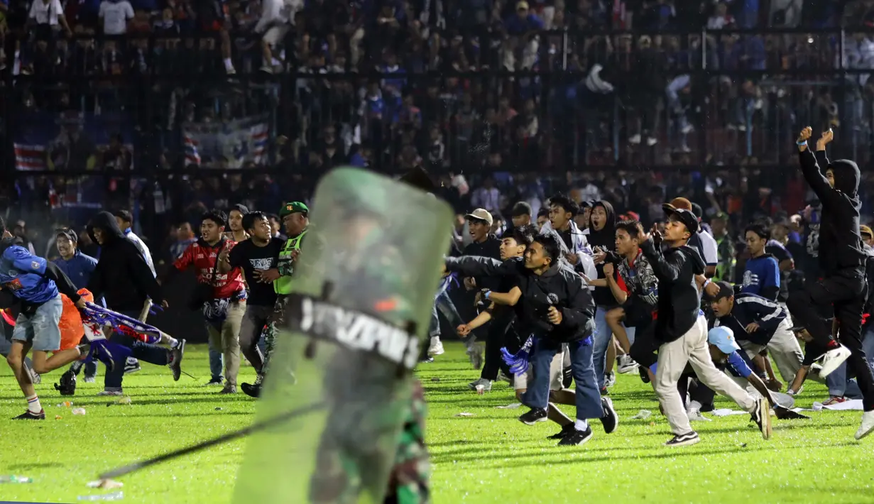 Suporter memasuki lapangan saat terjadi kerusuhan pada pertandingan sepak bola antara Arema Vs Persebaya di Stadion Kanjuruhan, Malang, Jawa Timur, 1 Oktober 2022. Kapolda Jawa Timur Irjen Pol Nico Afinta dalam jumpa pers di Kabupaten Malang, Jawa Timur, Minggu, mengatakan dari 127 orang yang meninggal dunia tersebut, dua di antaranya merupakan anggota Polri. (AP Photo/Yudha Prabowo)