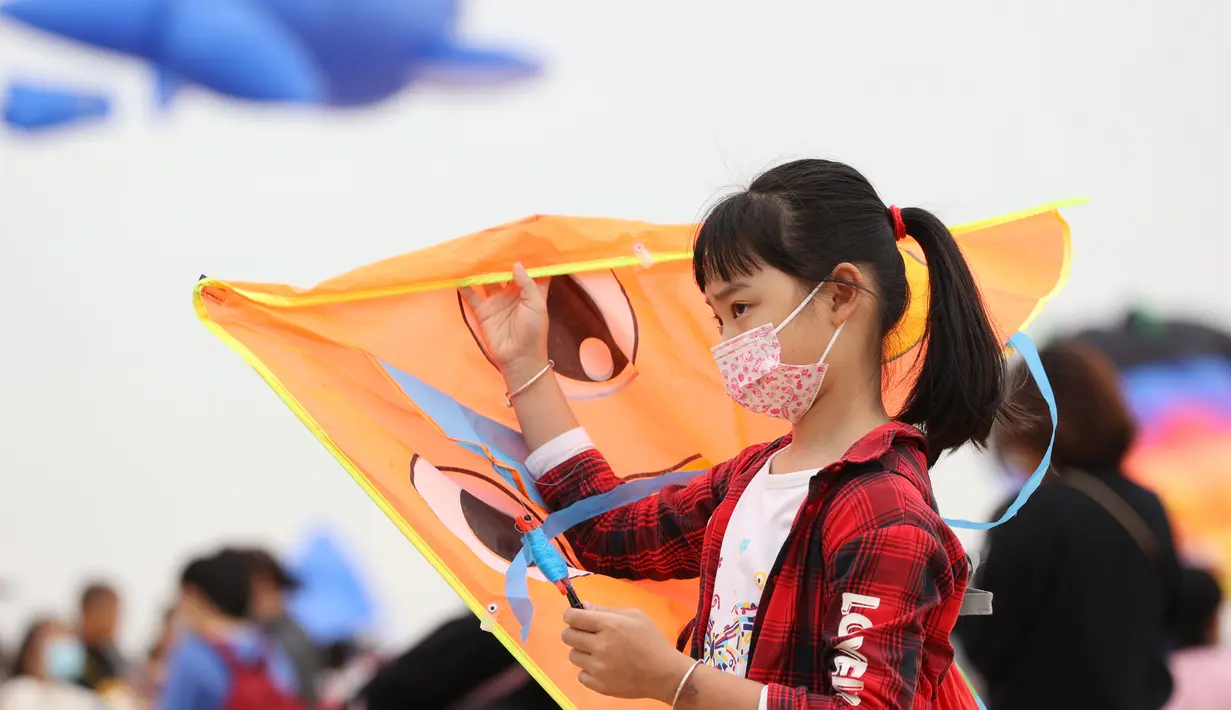 Seorang anak perempuan bersiap untuk menerbangkan layang-layang dalam festival layang-layang di Xiamen, Provinsi Fujian, China tenggara (21/11/2020). (Xinhua/Zeng Demeng)