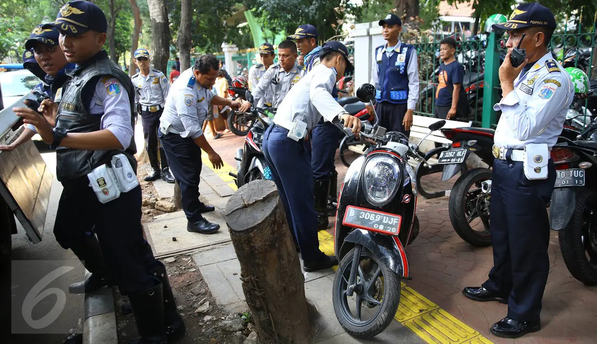 Petugas Dishub menertibkan sepeda motor yang parkir di sepanjang trotoar kawasan Kebon Sirih, Jakarta, Rabu (18/1). Puluhan motor diamankan serta digembosi dalam penertiban tersebut karena menutupi jalur pedestrian. (Liputan6.com/Immaniel Antonius)
