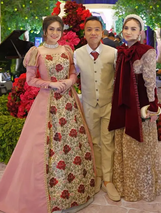 Celine Evangelista tampil mengenakan ball gown warna pink lengan panjang balon. Dress pub memiliki motif bunga mawar merah di bagian depan. Ia pun mengenakan kalung choker layering mutiara. [@aanstory]