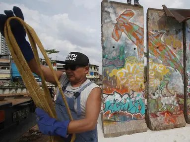  Seniman Teguh Ostenrik saat memasang bongkahan Tembok Berlin di RPTRA Kalijodo, Jakarta, Selasa (26/9). Empat segmen pecahan Tembok Berlin dan 14 "Patung Menembus Batas" untuk memperindah bekas lokalisasi Kalijodo. (Liputan6.com/Immanuel Antonius)