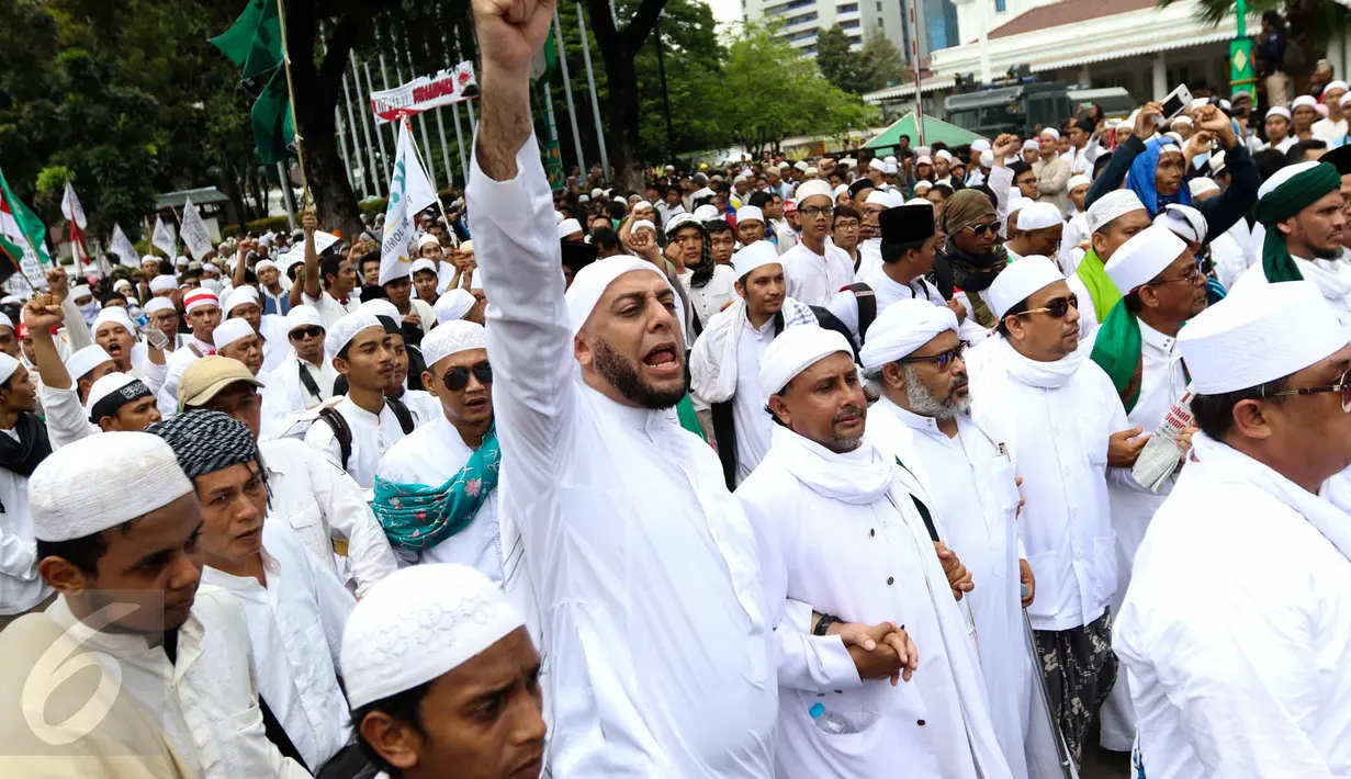 Ulama kondang Syekh Ali Jaber mengepalkan tangannya ke atas sambil mengucapkan kalimat takbir saat berjalan bersama massa aksi damai 4 November melewati Balai Kota Jakarta menuju ke Istana Merdeka, Jumat (4/11). (Liputan6.com/Faizal Fanani)